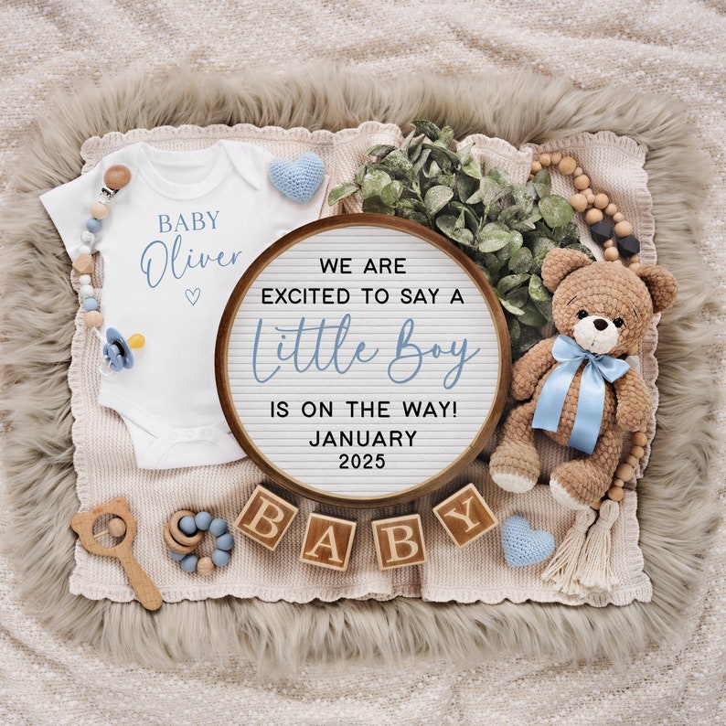 以下が含まれることがあります： 「BABY Oliver」と書かれた白いロンパースと、「WE ARE EXCITED TO SAY A Little Boy IS ON THE WAY! JANUARY 2025」と書かれたレターボードを使ったベビー発表。  「BABY」と綴られた木製のブロックと、青いリボンをつけたテディベアも写っています。