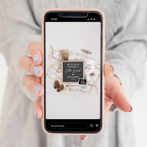 May include: A smartphone screen displaying a photo of a baby announcement. The photo shows a white blanket with a wooden sign that reads "We've been keeping a little secret. September 2023." There is a baby onesie that says "Baby Wilson" and a sonogram photo.
