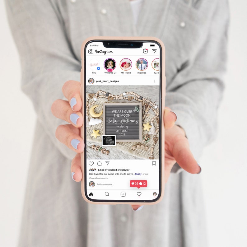 Peut inclure: L'&eacute;cran d'un smartphone affichant un post Instagram annon&ccedil;ant l'arriv&eacute;e d'un b&eacute;b&eacute;. Le post pr&eacute;sente un panneau en ardoise avec le texte "We are over the moon! Baby Williams arriving August 2023". Le panneau est entour&eacute; de diverses d&eacute;corations sur le th&egrave;me du b&eacute;b&eacute;, notamment une lune croissante, des &eacute;toiles et une guirlande de perles en bois.