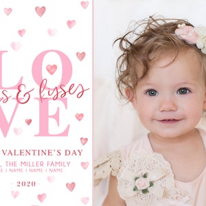 May include: A pink and white Valentine's Day card featuring a photo of a baby girl with curly hair wearing a pink dress and a flower headband. The card reads "LOVE hugs & kisses" in pink lettering with a pink heart. The card also says "HAPPY VALENTINE'S DAY LOVE, THE MILLER FAMILY NAME I NAME I NAME I NAME 2020-."