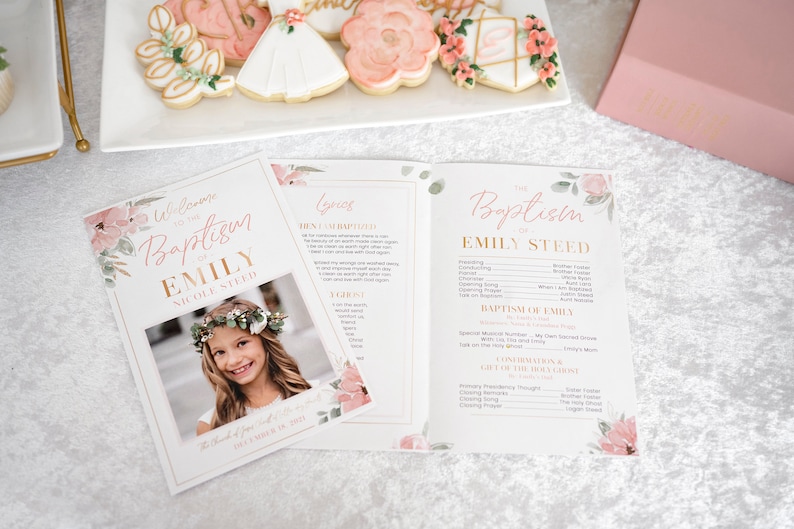 May include: A pink and gold baptism program with floral designs and a photo of a young girl. The program includes the order of service, lyrics, and a section for the baptism of Emily.