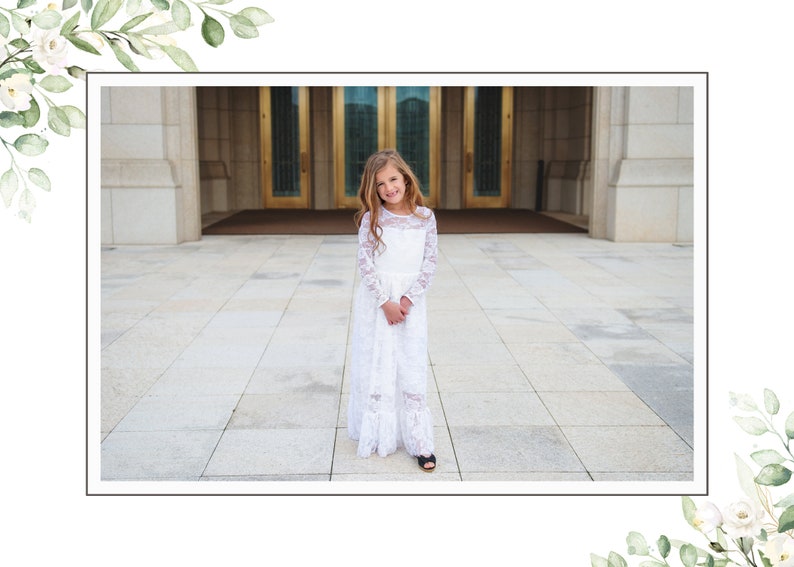 May include: A young girl wearing a white lace dress stands in front of a building with large golden doors. She is smiling and looking at the camera.