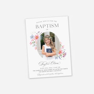 May include: A baptism invitation with a photo of a young girl wearing a floral crown and holding a book. The invitation includes the text "PLEASE JOIN US FOR THE BAPTISM OF" and the name "Taylor Olsen". Floral accents in pink, blue, and purple surround the photo.