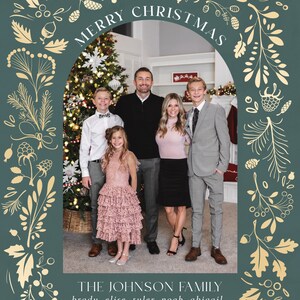 May include: A Christmas card featuring a family of five standing in front of a decorated Christmas tree. The card has a green background with gold floral designs and the text "Merry Christmas" and "The Johnson Family" in a gold font. The text "brady. elise. tyler. noah. abigail" and "2023" are also included in gold font.