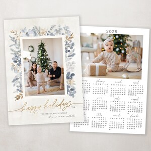 May include: A Christmas card with a watercolor floral border in shades of blue and gold. The card features a photo of a family of three standing in front of a Christmas tree. The text "Happy Holidays" is written in gold script. The card also includes a 2025 calendar.