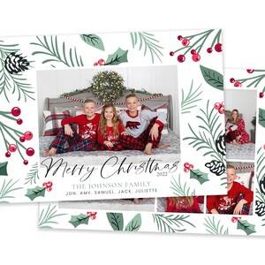 May include: A Christmas card with a white background and a green and red holly pattern. The card features a photo of a family of five in matching pajamas. The text "Merry Christmas 2022" is written in black script. The text "The Johnson Family" is written in gray below the photo. The text "Jon, Amy, Samuel, Jack, Juliette" is written in gray below the family name.