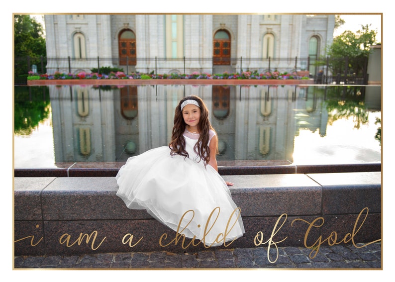 May include: A young girl in a white dress sits on a stone ledge in front of a large building with a reflecting pool in the foreground. The text "i am a child of God" is written in gold script on the ground in front of her.