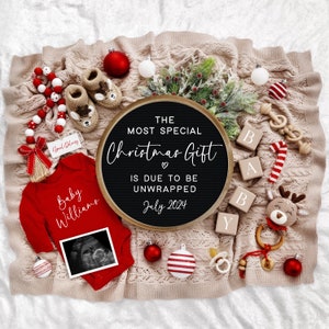 Pu&ograve; includere: Una lavagna nera con lettere bianche che compongono la frase "The Most Special Christmas Gift is Due to Be Unwrapped July 2024". La lavagna &egrave; circondata da decorazioni natalizie rosse e bianche, un body da bambino rosso con il testo "Baby Williams" e un'immagine di ecografia, e blocchi di legno che compongono la parola "Baby".