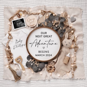 May include: A wooden sign with the text "Our Next Great Adventure Begins March 2024" surrounded by baby items, including a onesie, a rattle, a stuffed animal, and a bottle. The onesie has the text "Baby Phillips" on it.