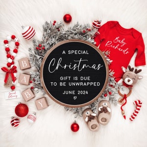 May include: A black letter board with the text "A Special Christmas Gift is Due to Be Unwrapped June 2024" surrounded by red and white ornaments, a red onesie with the text "Baby Richards", and a brown and white stuffed animal.