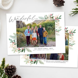 Op de afbeelding: Een kerstkaart met een aquarelrand van groene bladeren en rode bessen. De kaart toont een familiefoto van zeven mensen die voor een houten brug staan. De tekst op de kaart luidt "It's a Wonderful Life" en "The Smith Family 20XX Matt | Andrea | Jax | Laney | Liv".