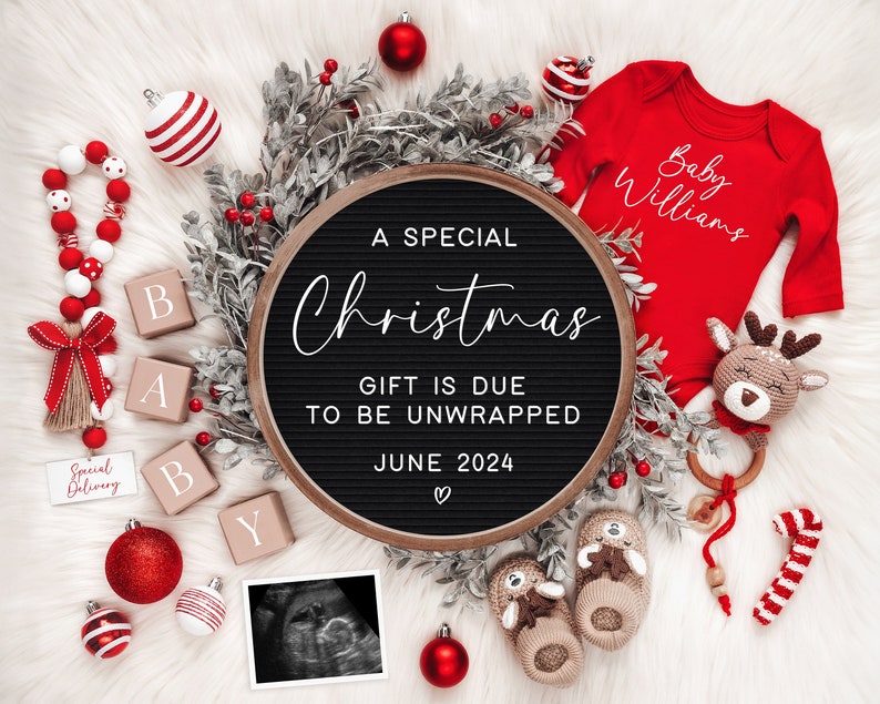May include: A black letter board with the text "A Special Christmas Gift is Due to be Unwrapped June 2024" surrounded by red and white Christmas decorations, including a red baby onesie with the text "Baby Williams" and a crocheted reindeer toy.