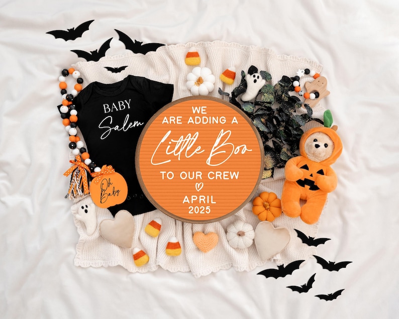 May include: A Halloween-themed baby announcement with a letter board that reads "We are adding a little boo to our crew April 2025". The letter board is surrounded by a variety of Halloween decorations, including bats, pumpkins, and a stuffed pumpkin-shaped bear.
