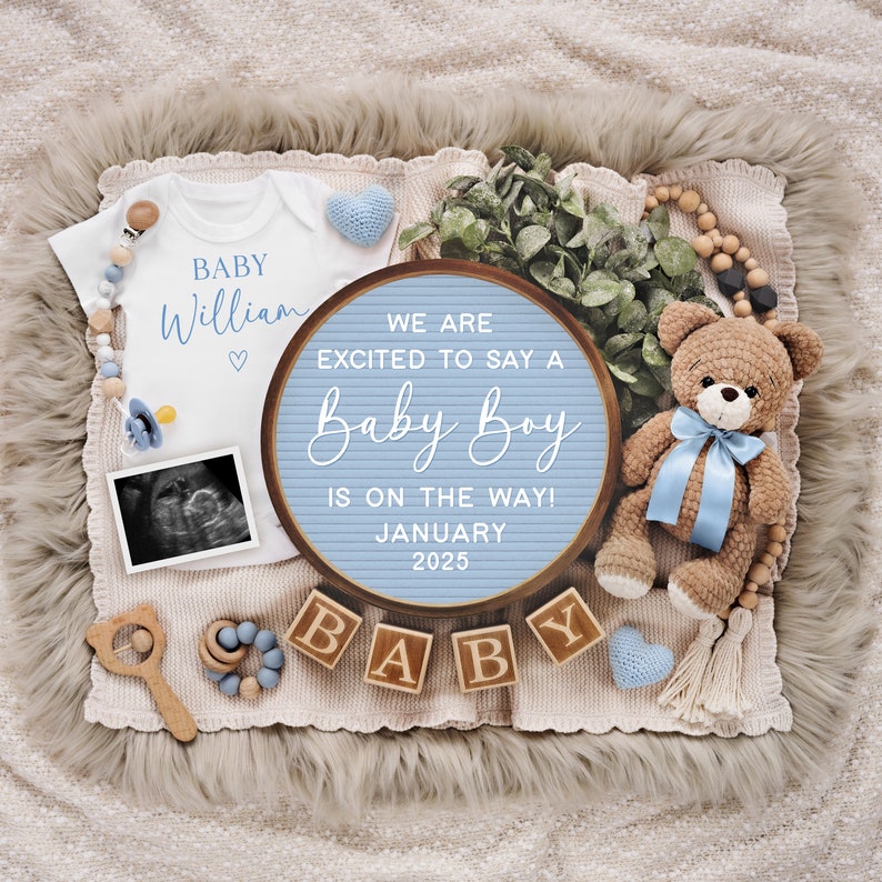 May include: A blue and white letter board with the text "We are excited to say a Baby Boy is on the way! January 2025". The board is surrounded by baby items, including a white onesie with the name "William" on it, a teddy bear, and wooden blocks that spell out "BABY".