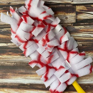 May include: White and red dog toy with a yellow handle. The toy is made of soft, fuzzy material and is designed to be interactive for dogs.