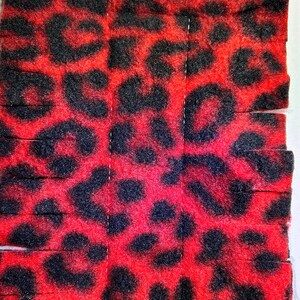 May include: Red and black leopard print fabric cut into strips. The fabric is soft and fuzzy.