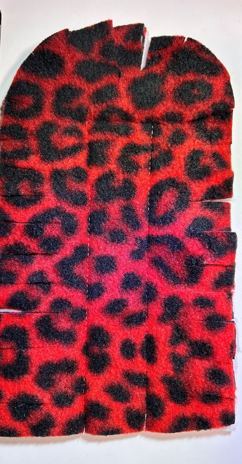 May include: Red and black leopard print fabric cut into strips. The fabric is soft and fuzzy.