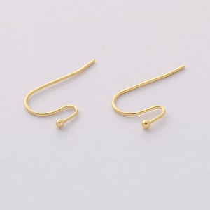 May include: A pair of gold-toned earring hooks with a small ball at the end of each hook.