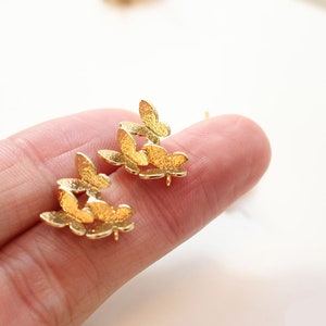 May include: A pair of gold-tone earrings featuring a cluster of small butterfly shapes.