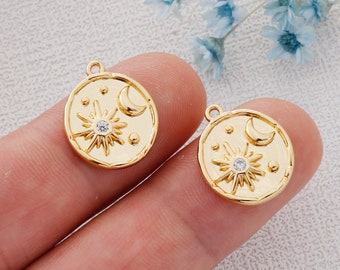 May include: Two gold-tone metal charms featuring a sun and moon design with a clear rhinestone in the center of the sun. Each charm has a small loop at the top for attaching to a necklace or bracelet.
