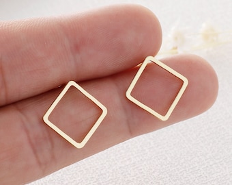 May include: A pair of gold-toned geometric square earrings. The earrings are simple and minimalist in design.