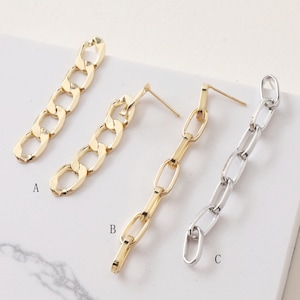 Pode incluir: Três pares de brincos pendentes com elos de corrente. O primeiro par é dourado com elos grossos. O segundo par é dourado com elos mais finos. O terceiro par é prateado com elos finos.