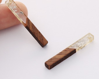 Puede incluir: Dos pendientes rectangulares de madera y resina transparente con un patrón de veta de madera en un lado y resina transparente con motas de oro en el otro.