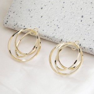 Può includere: Un paio di orecchini a cerchio dorati con un design a triplo cerchio. Gli orecchini sono in metallo e hanno uno stile semplice e moderno.
