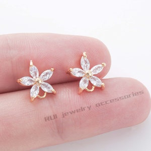 May include: A pair of gold-tone earrings with a flower design. Each earring features a five-pointed star with clear cubic zirconia stones.