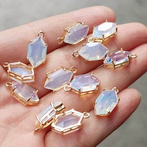 May include: A collection of 10 gold-toned metal charms with iridescent glass octagons. Each charm has a loop for attaching to jewelry.