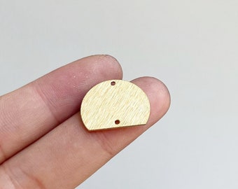 Op de afbeelding: Een gouden metalen halve cirkelvormige bedel met twee gaten om sieradenbeslag aan te bevestigen.