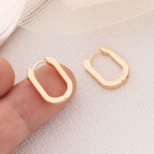 May include: A pair of gold-toned hoop earrings with a rectangular shape. The earrings are simple and elegant.