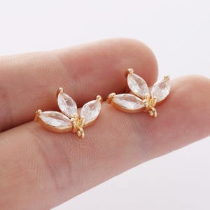 May include: Two gold-tone leaf-shaped charms with clear crystal accents. Each charm has three crystal accents in the shape of marquise-cut stones.