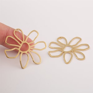May include: Two gold metal flower-shaped charms with a hole at the top for attaching to jewelry or other crafts.