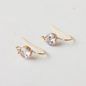 May include: A pair of gold-tone earring hooks with clear round cubic zirconia stones.