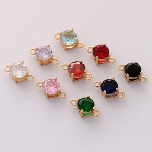 May include: Assortment of eight gold-tone connector charms with round, faceted, colored stones. The stones are clear, light blue, lavender, pink, red, green, black, and blue.