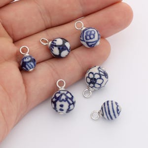 Puede incluir: Seis pequeñas cuentas redondas de cerámica con aros plateados. Las cuentas son blancas con diseños florales y geométricos azules. Ideales para la creación de joyas o manualidades.