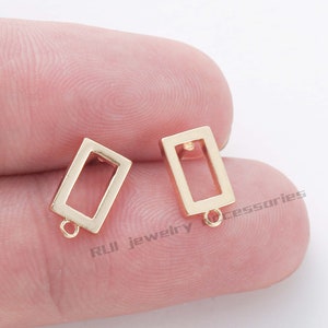 May include: Two gold-toned metal earring blanks with a rectangular shape and a small loop at the bottom. The blanks are designed to be filled with resin or other materials.