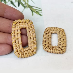 Könnte beinhalten: Zwei geflochtene ovale Ringe aus Rattan mit einem Loch in der Mitte. Die Ringe sind aus natürlichem braunem Rattan gefertigt und perfekt, um Ihren Bastelarbeiten einen Hauch von Boho-Stil zu verleihen.