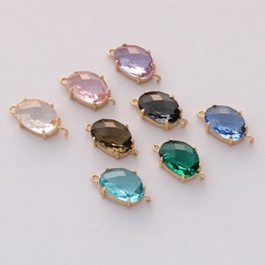 Puede incluir: Siete conectores ovalados de vidrio con detalles en metal dorado. Los conectores son de varios colores, incluyendo transparente, rosa, lavanda, azul, verde, marrón y negro.