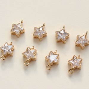 Puede incluir: Ocho abalorios dorados en forma de estrella con detalles de cristal transparente. Los abalorios tienen un bucle en la parte superior para sujetarlos a joyas u otras manualidades.