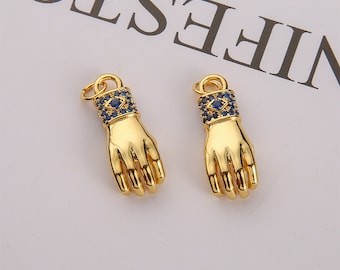 May include: Two gold-toned hand charms with blue crystal accents. Each charm features a detailed hand design with a small eye symbol on the wrist.