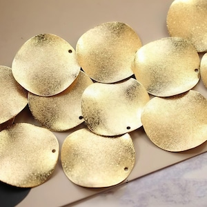 May include: A group of gold-colored metal circles with a textured surface. The circles have a hole in the center.