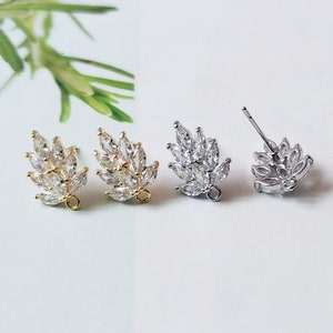 May include: Two pairs of gold and silver earring findings with a leaf design featuring clear cubic zirconia stones.