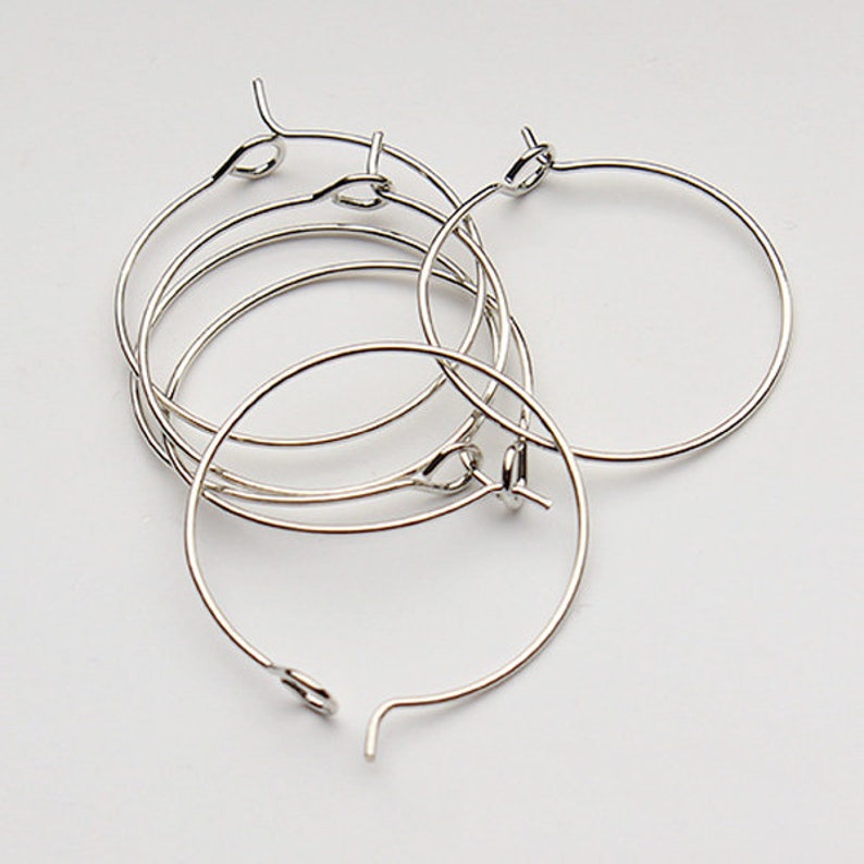 May include: Five silver hoop earrings with a simple, circular design. The hoops are all the same size and are made of a thin, wire-like material.