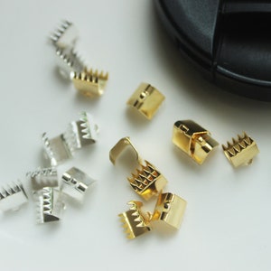 May include: A collection of gold and silver metal clasps for jewellery making. The clasps are small and have a decorative design.