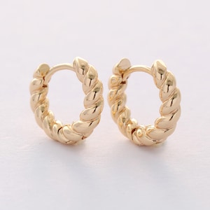 May include: A pair of gold hoop earrings with a twisted rope design.