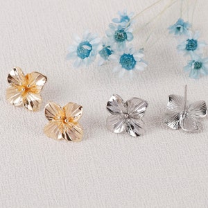 May include: A pair of flower-shaped earrings, one gold and one silver. The earrings are simple and elegant, with a delicate design.
