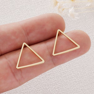 May include: A pair of gold triangle shaped earrings. The earrings are simple and minimalist.