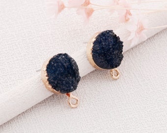 May include: A pair of gold-toned earrings with black agate stone accents. The earrings have a round shape and a textured surface. Each earring has a small loop at the bottom.